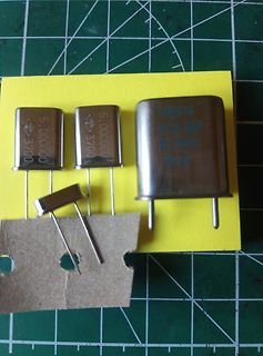 Drei Metallgehäuse-Schwingquarze auf gelbem Papier