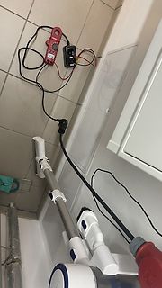 Strommesszange und Staubsauger auf Fliesenboden