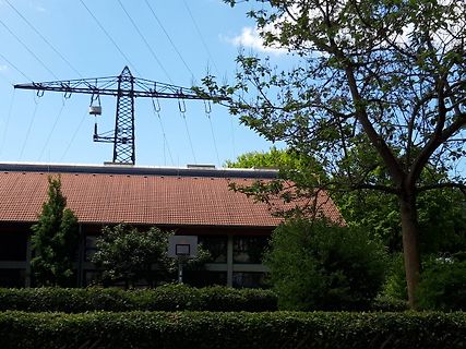 Strommast und Haus unter blauem Himmel