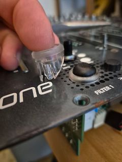 Hand hält Kunststoffteil über Elektronikgerät