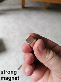 Hand hält kleinen starken Magneten