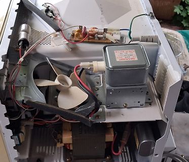 Innenansicht eines geöffneten Elektrogeräts mit Transformator und Lüfter