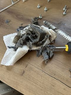 Dreckige Watte und Schrauben auf Holztisch