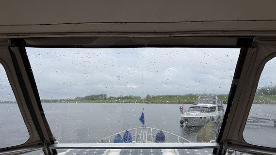 Blick aus einem Boot auf einen See bei Regen