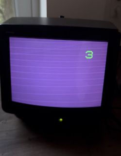 Abfotografierter alter Röhrenfernseher mit lila Bild und der Zahl 3