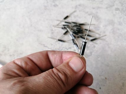 Hand hält eine Diode vor einem Haufen weiterer Dioden