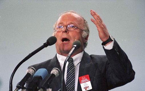 Mann mit Brille spricht vor Mikrofonen