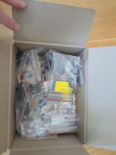 Offener Karton mit in Plastikbeuteln verpackten Kleinteilen