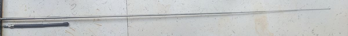 Lange Metallstange und schwarzes Bauteil auf hellem Untergrund