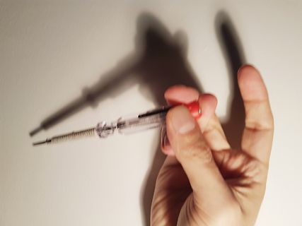 Hand hält eine Spritze