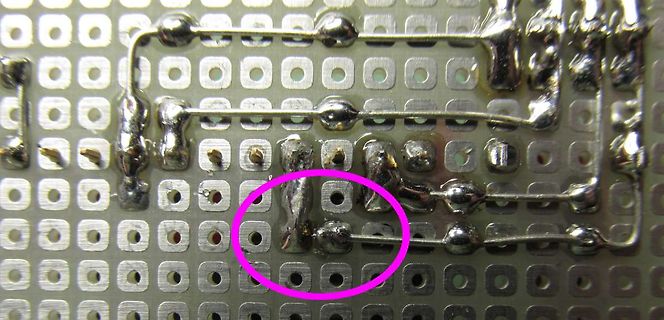 Nahaufnahme einer geätzten Lochrasterplatine mit Lötstellen