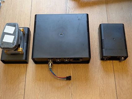 Drei schwarze Elektronikgehäuse auf Holzuntergrund