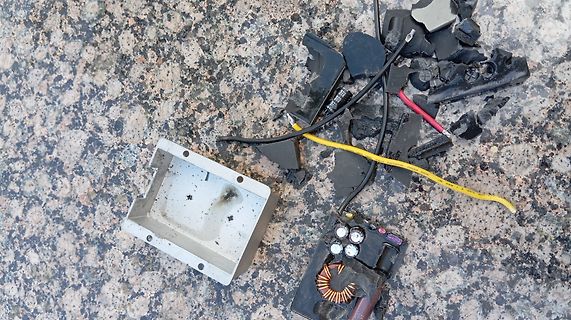 Zerstörte Elektronikkomponenten und Gehäuseteile auf Steinuntergrund