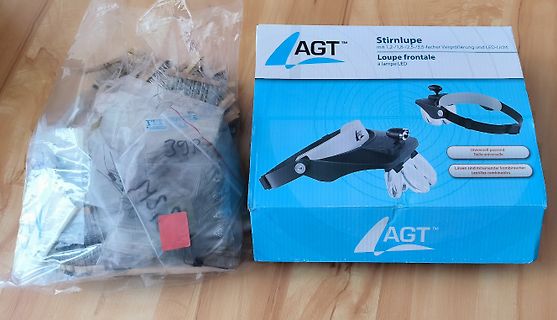 Verpackung einer AGT Stirnlupe und Inhalt in Plastikbeutel