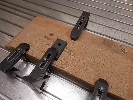 Holzbrett mit Metallklemmen auf Metalluntergrund