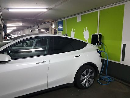 Weißes Elektroauto an Ladestation in Tiefgarage