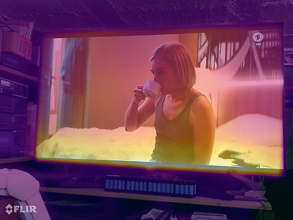 Abfotografierter Fernseher mit einer Frau beim Kaffeetrinken