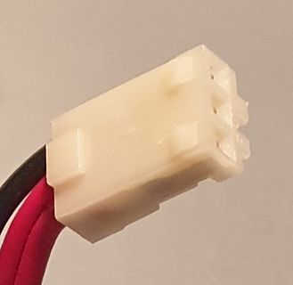 Weißer Kunststoffstecker mit roten und schwarzen Kabeln