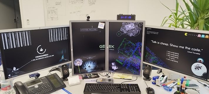 Arbeitsplatz mit drei Monitoren und Peripherie