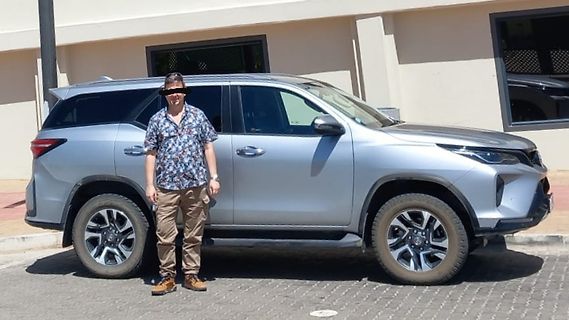 Mann steht neben silbernem SUV