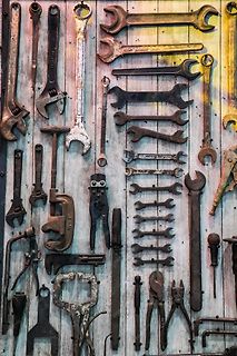 Verschiedene alte Metallwerkzeuge an einer Holzwand