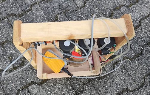 Elektronischer Aufbau in Holzrahmen mit Schläuchen und gelbem Schalter