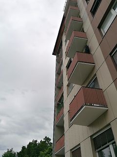 Hochhaus mit Balkonen unter bewölktem Himmel