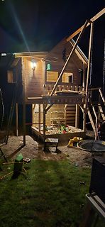Holzspielhaus mit Sandkasten und Schaukel im Garten