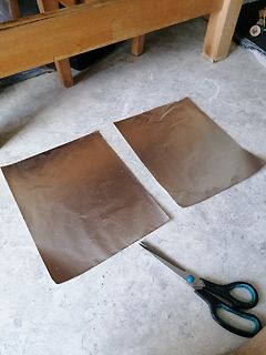 Zwei Kupferfolien und eine Schere auf Boden
