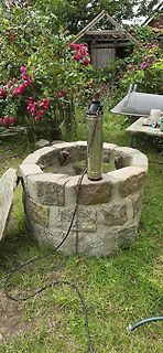 Metallzylinder auf einem gemauerten Brunnen