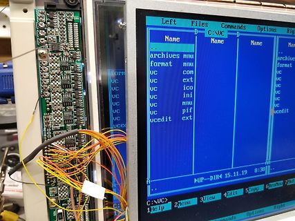 Leiterplatte mit bunten Kabeln und Computerbildschirm