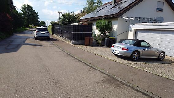 Straße mit parkenden Autos und einem Haus