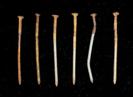 Sechs verrostete Nägel auf schwarzem Hintergrund