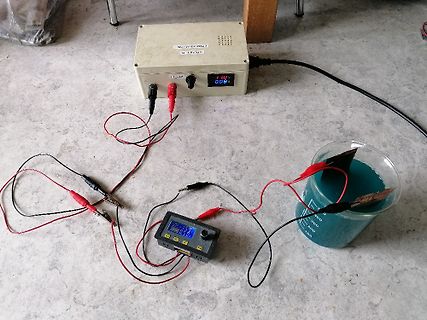 Versuchsaufbau mit Netzteil, Messgerät und Elektrolysebecher