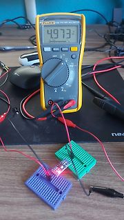 Multimeter und Breadboard-Aufbau mit leuchtender LED