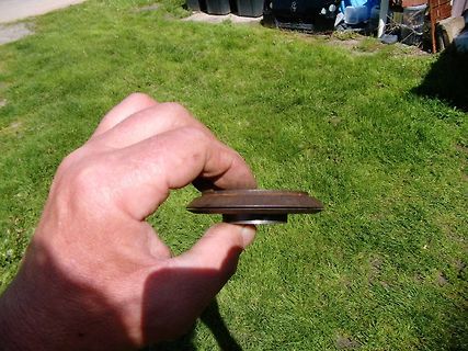 Hand hält ein flaches Metallobjekt im Freien