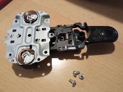 Zerlegtes elektronisches Bauteil mit Metallplatte und Schrauben