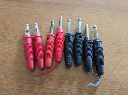Sieben Messkabel mit Bananensteckern auf Holzuntergrund