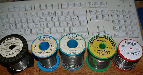 Vier Rollen Lötdraht vor einer Tastatur