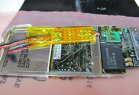 Geöffnete Elektronik mit Leiterplatte und gelbem Klebeband