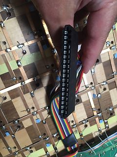 Hand hält Flachbandkabel mit Stecker über Leiterplatte