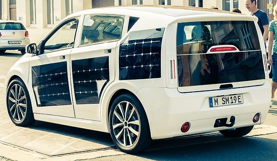 Weißes Elektroauto mit Solarzellen an der Seite