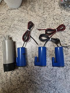Drei blaue Schwimmerschalter mit Kabeln und eine graue Pumpe