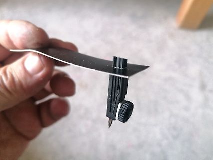 Hand hält eine kleine Klemme mit Metallplatte
