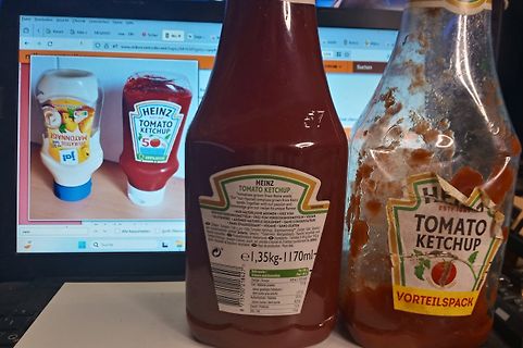 Abfotografierte Ketchupflaschen vor einem Monitor