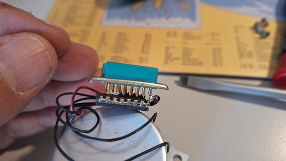 Hand hält Bauteil mit blauer Komponente und Drähten