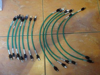 Mehrere grüne Kabel mit Steckverbindern auf Fliesen