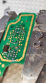 Nahaufnahme einer grünen Leiterplatte in einem Schraubstock
