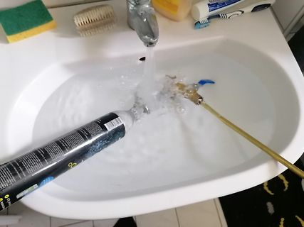 Dose und Gegenstand in Waschbecken unter fließendem Wasser