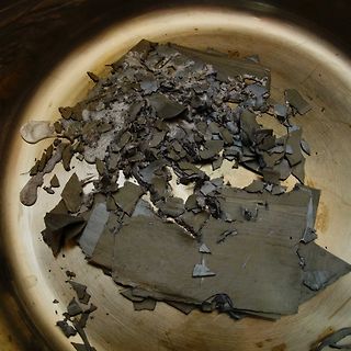 Zerstörte Bauteile oder Materialreste in einem Metallgefäß
